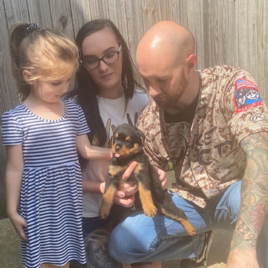 A family holding a black puppy