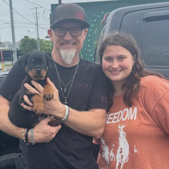 A man and a woman together and the man holding a puppy